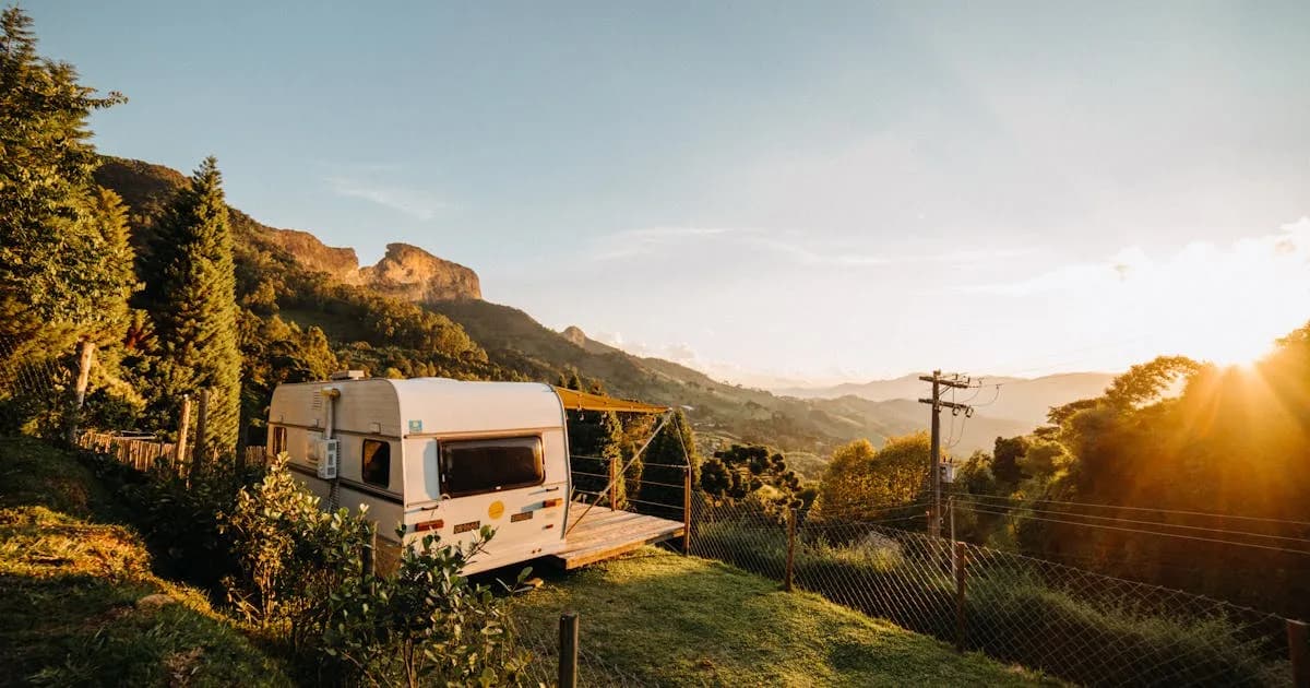 Caravan parked on a lush green hillside at sunset