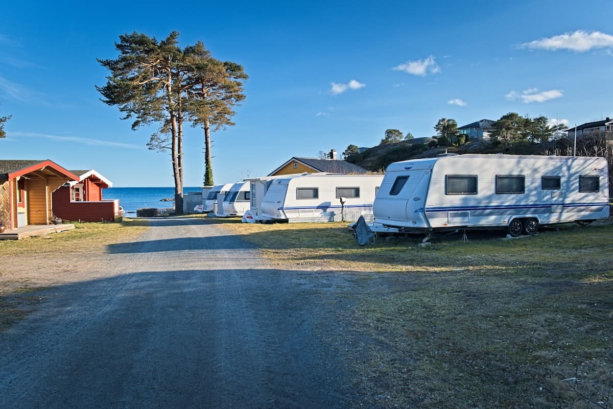 Row of modern white towable caravans lined up at a scenic caravan park with ocean views