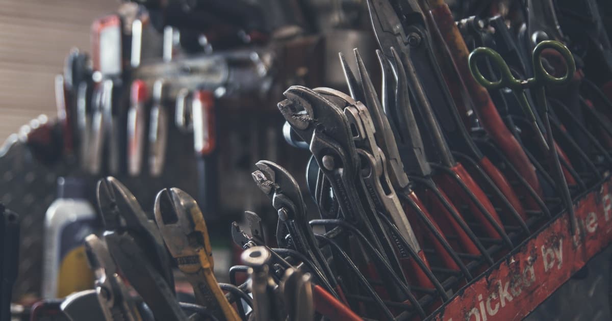 Assortment of hand tools including pliers and wrenches in a workshop tool rack