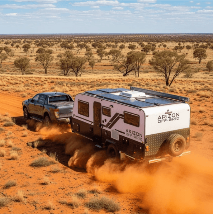 Arizon Off-Grid hybrid caravan being towed by a pickup truck through the red Australian outback